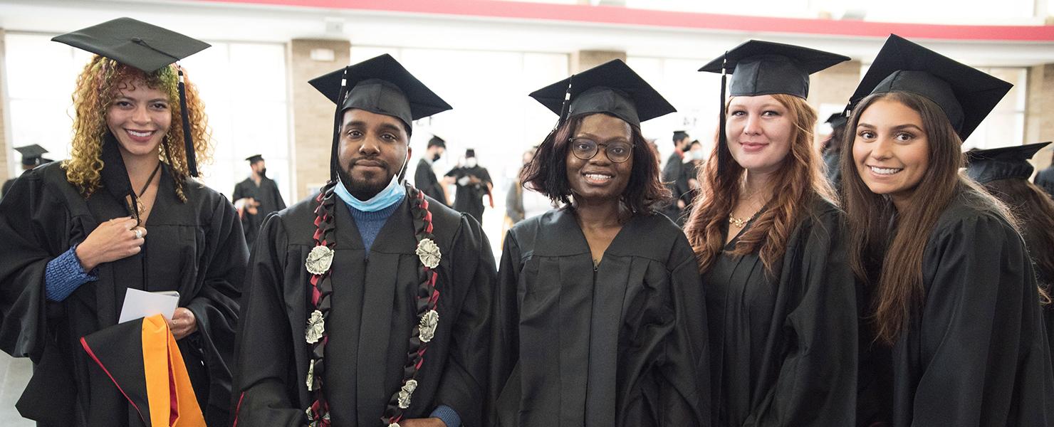 two students celebrating graduation in front of alumni donor wall